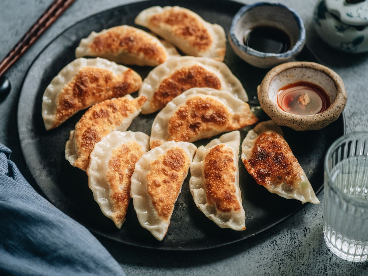Pan-fried egg and pepper dumplings arranged on a plate with dipping sauces.