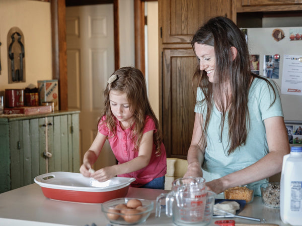 A young girl baking with her mother.