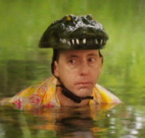 A man up to his shoulders in water, wearing a hat shaped like an alligator head