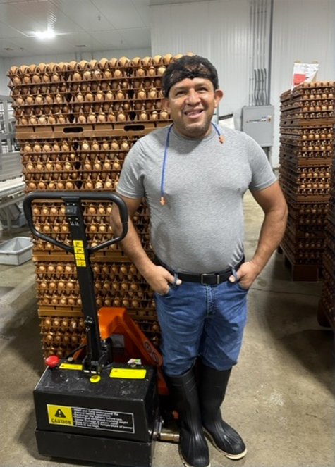 A man standing in front of a pallet loaded with cartons of eggs