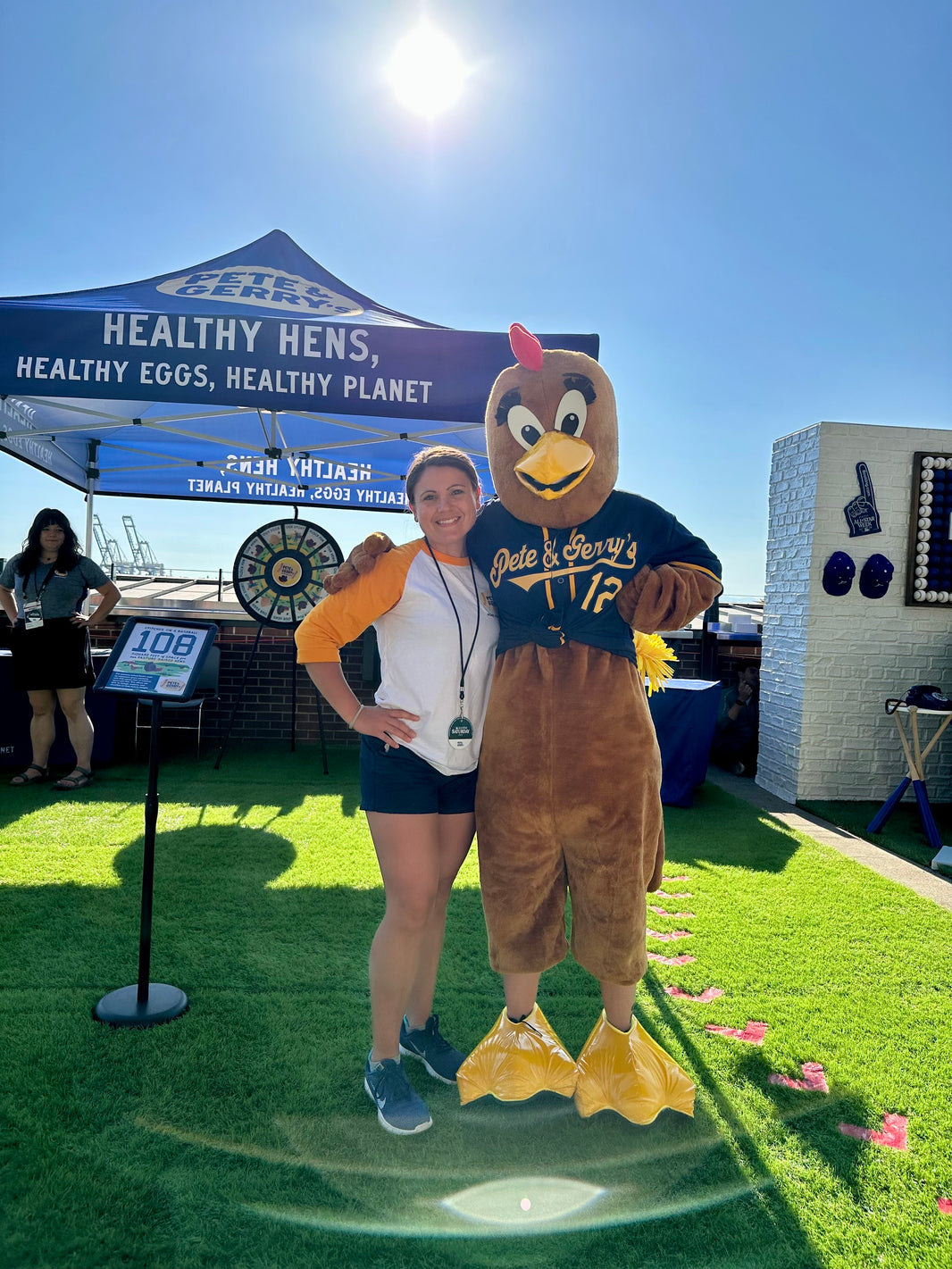 A woman standing with a rooster mascot