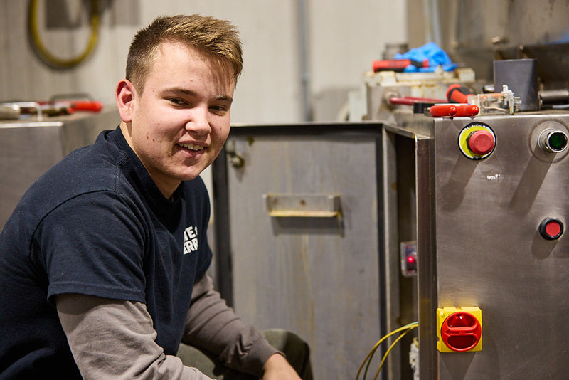 Person in a workshop setting with machinery and tools in the background